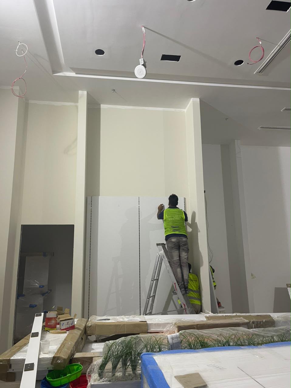 Contractor finishing a drywall partition from a ladder