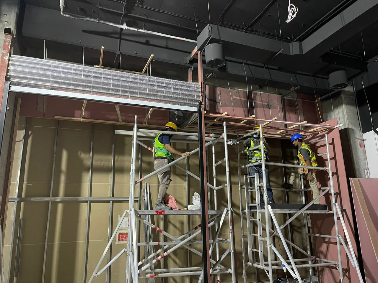 Contracting crew assembling ceiling framework from scaffolding