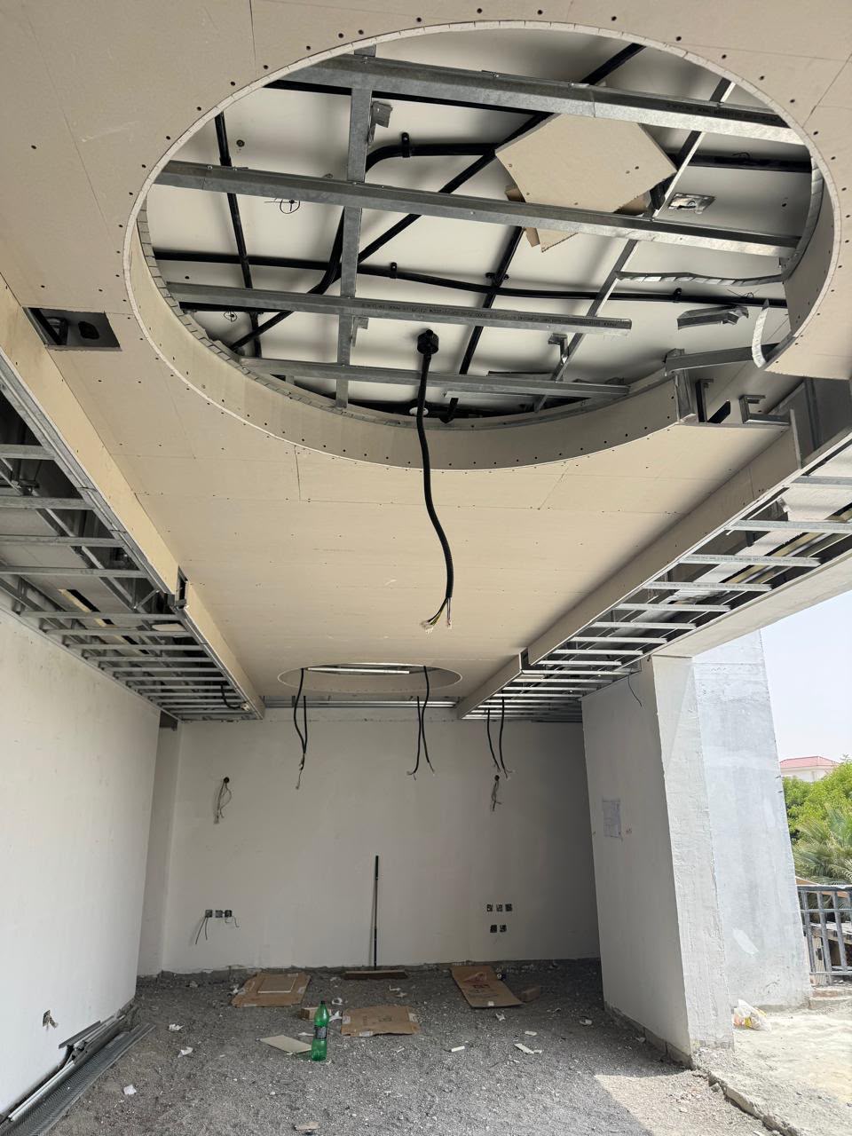 Circular gypsum ceiling feature under construction with exposed metal framing