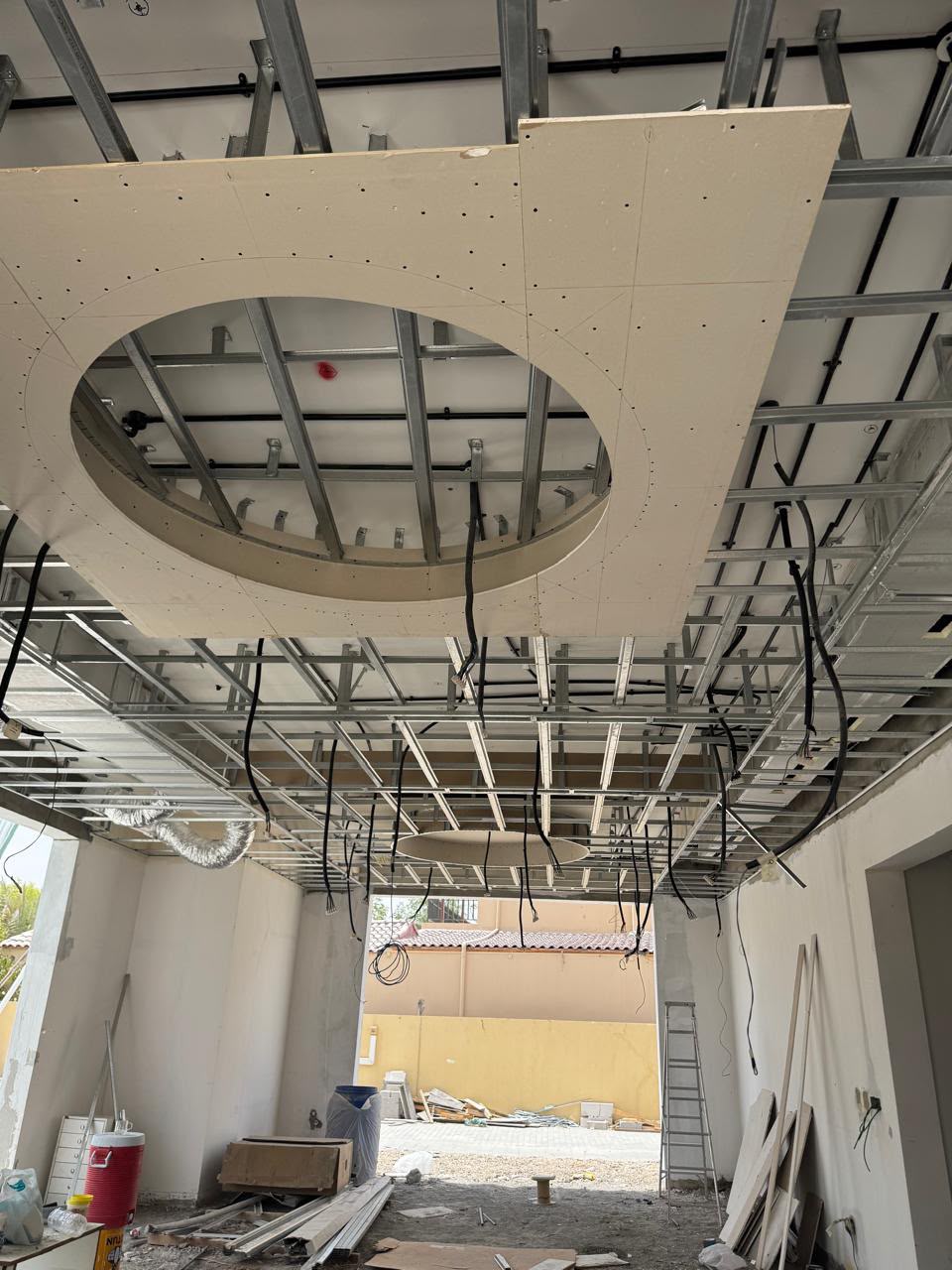 Curved gypsum ceiling cutout with cabling, viewed from below in a villa under construction