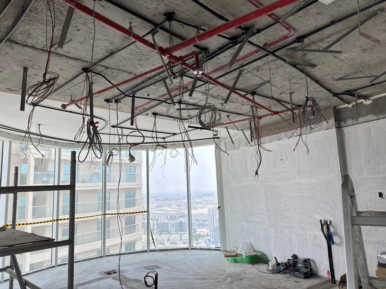 High-rise apartment interior mid-fit-out with exposed wiring and city skyline view