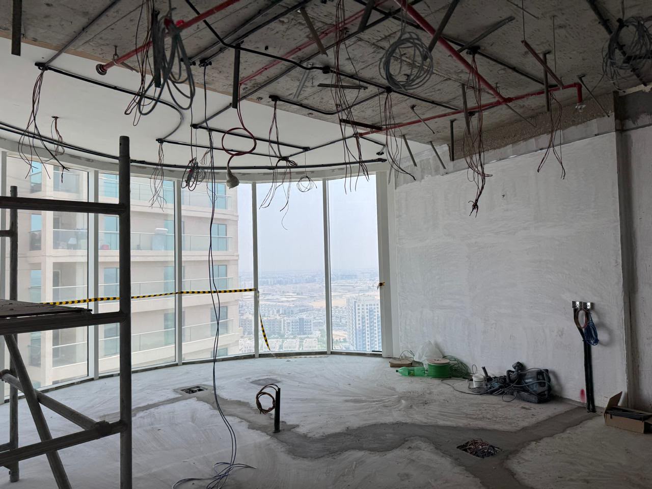 High-rise apartment under renovation with hanging cables and panoramic city view