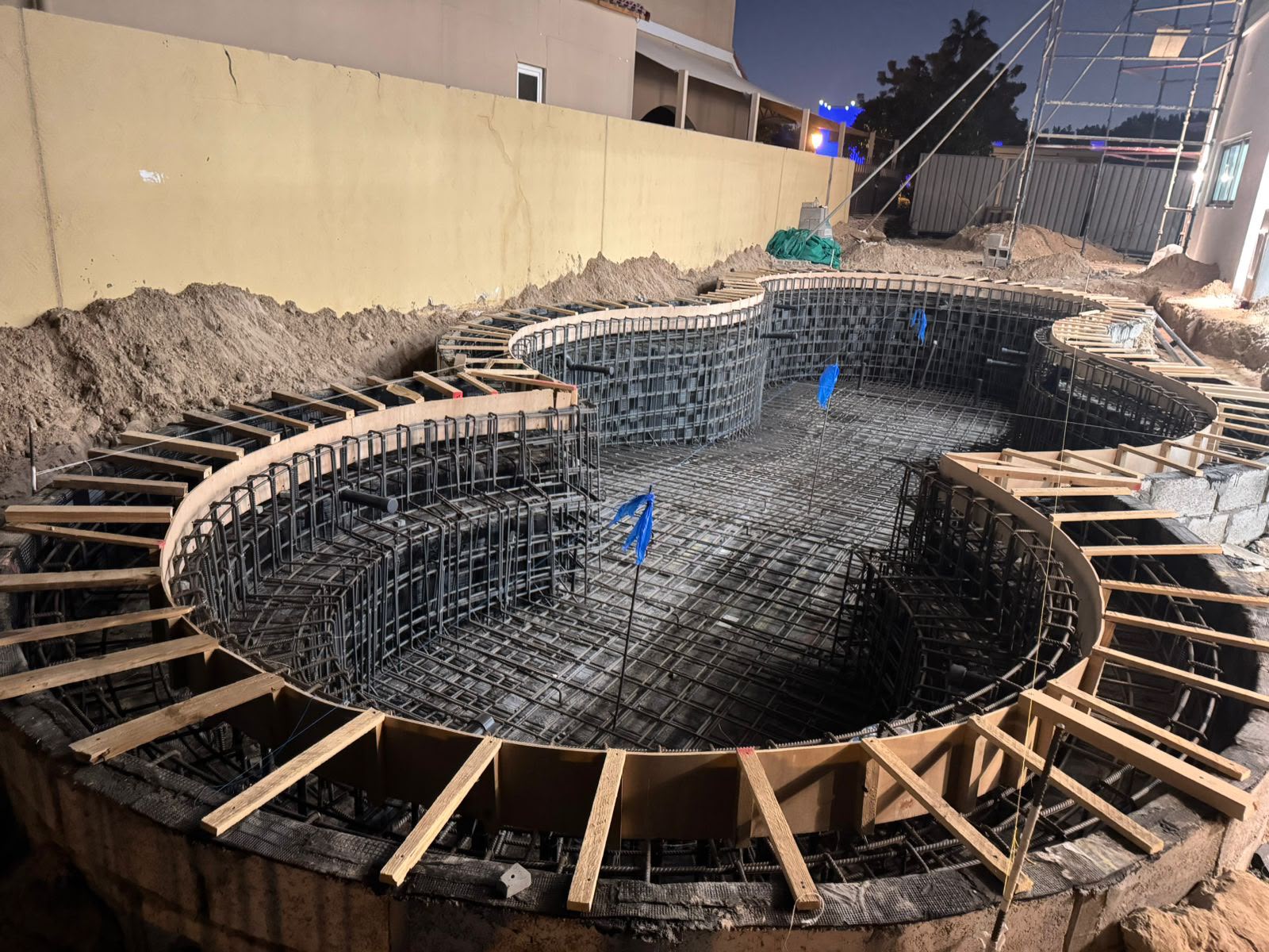 Curved swimming pool reinforcement and formwork construction at night