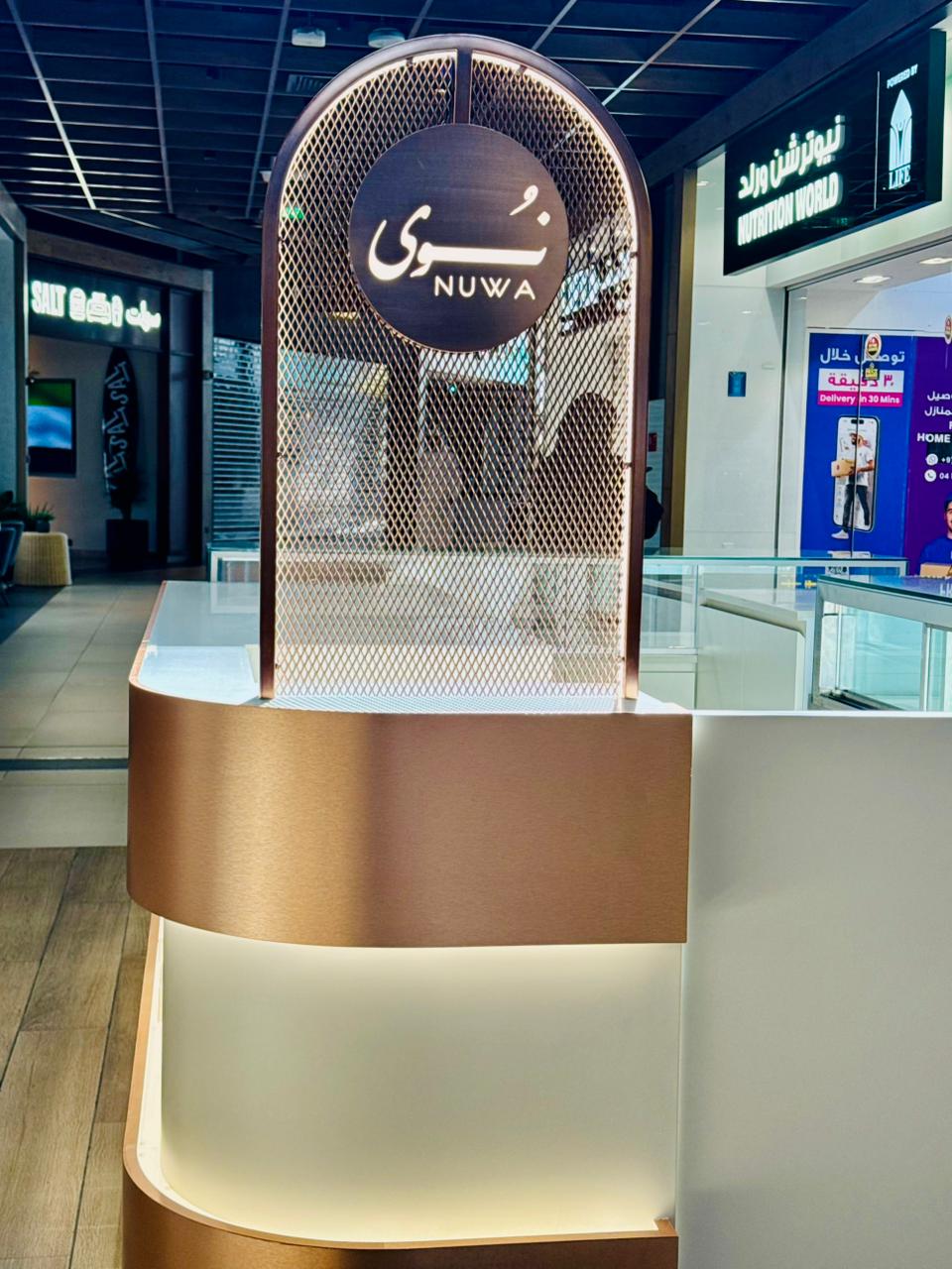 Illuminated branded kiosk archway signage in a shopping mall corridor